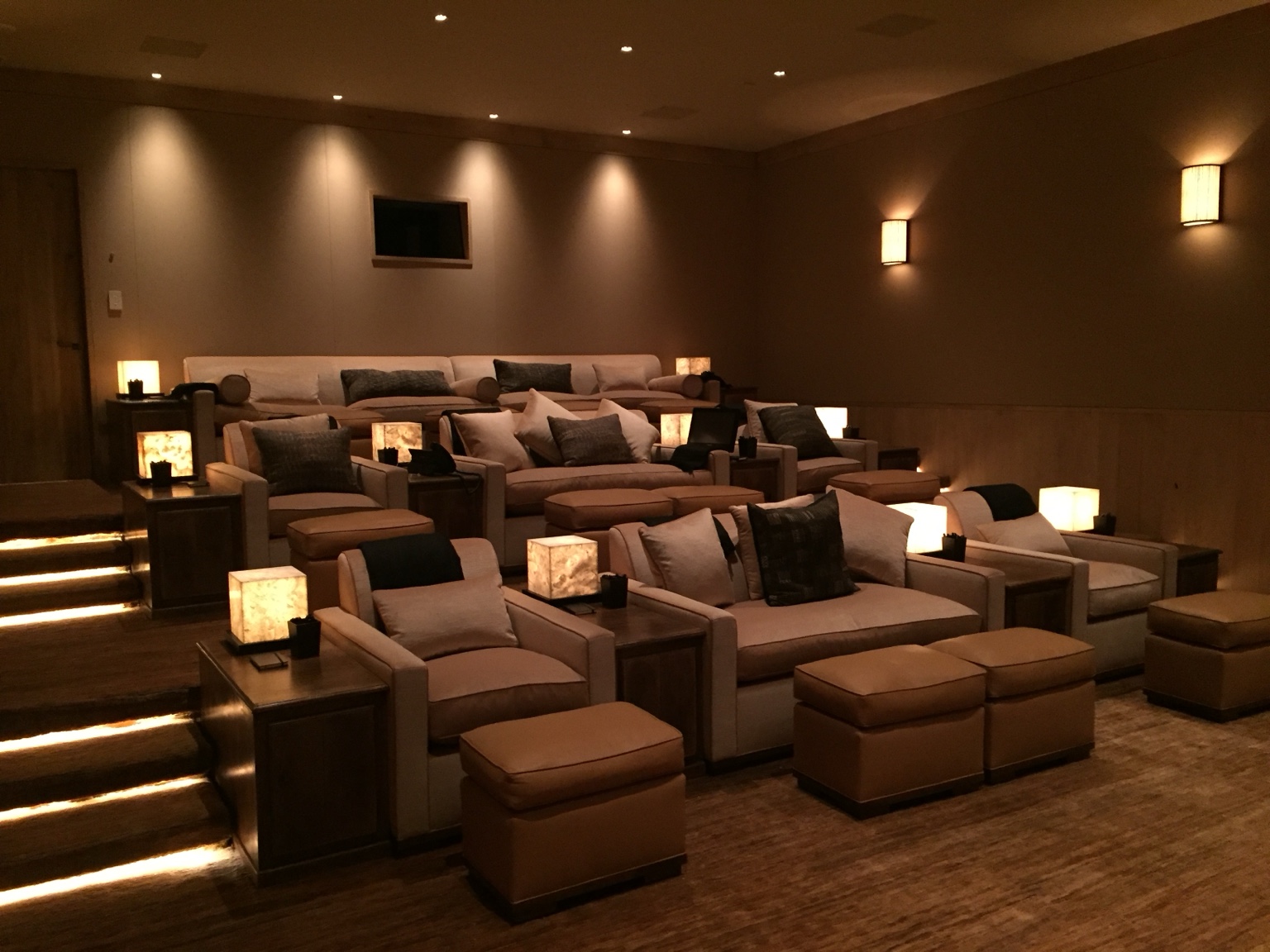 Private home theater with tiered lounge seating and warm architectural lighting